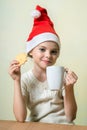 ÃÂ¡ute girl in Santa Claus hat eat cookies.